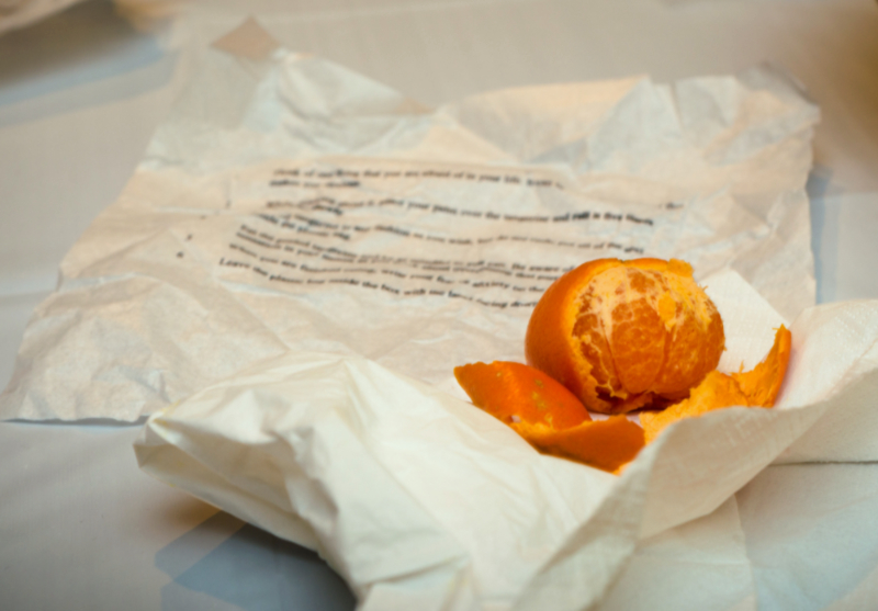 a peeled tangerine resting on top of flattened out crumpled tissue paper with instructions printed on it