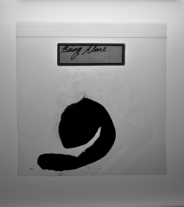 black and white close up of decomposings tangerine peel in a ziplock bag with a label that reads 'being alone'